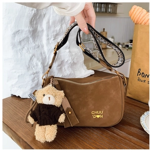 Détail du sac oreiller en daim marron avec bandoulière jacquard et breloque ours