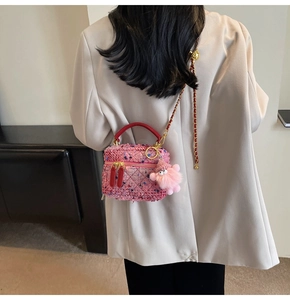 Detailed back view of pink tweed box bag with gold chain strap and plush monster charm