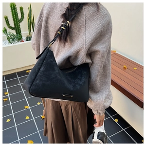 Chic black hobo shoulder bag with gold hardware and adjustable strap on a female model