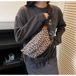Detailed view of leopard print crossbody chest bag with orange brand tag and woven strap