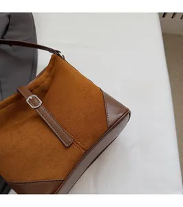 Gros plan sur un sac seau marron en daim et cuir avec boucle en métal argenté