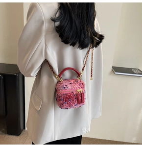 Detail of pink plaid tweed mini bucket bag with chain strap and red leather handle