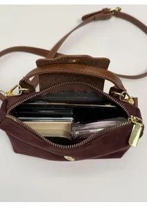Internal capacity of contrast color suede crossbody bag showing phone and cosmetics