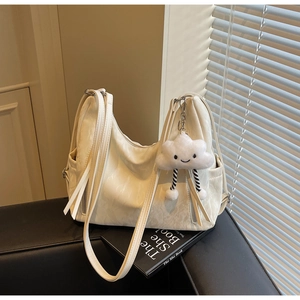 Detail view of cream leather hobo bag with cloud pendant on a leather sofa