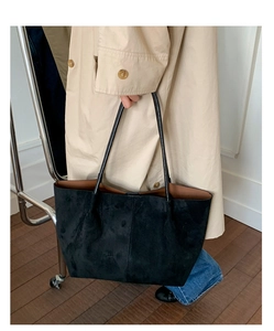 Close-up of black suede tote bag with contrast brown interior and long shoulder handles