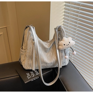Detail of silver pleated tote bag with tassels and a cute white plush cloud charm