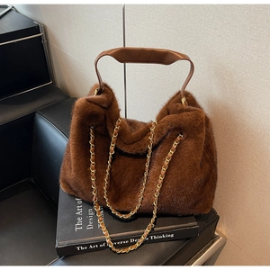 Detailed view of dark brown faux fur tote bag with golden metal chain strap and leather handle