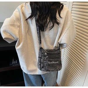 Back view of model wearing a vintage grey denim crossbody bag with multiple zipper pockets