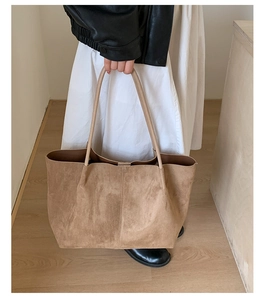 Suede camel tote bag on model's shoulder showing large capacity and minimalist stitching