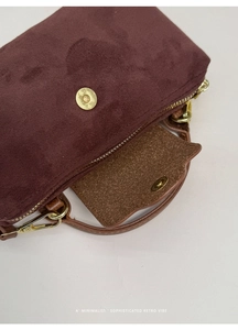 Detailed close-up of dark wine red suede texture with decorative gold snap button