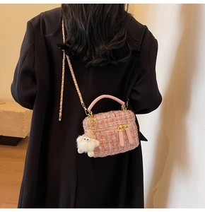 Pink tweed mini chain bag with cute plush pendant shown on a black winter coat