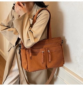 Detail of caramel corduroy tote bag featuring multiple zip pockets and woven zipper pulls