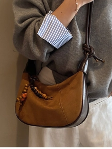 Retro brown suede hobo bag worn by model, featuring bohemian bead charms and leather straps