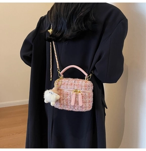 Close-up of pink tweed mini bag with gold bear charm and plush doll keychain on model