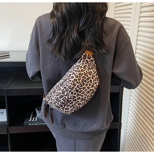 Detail view of leopard print crossbody bag with orange logo tag on durable canvas