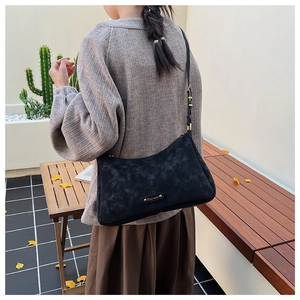 Detail of black matte leather shoulder bag with gold metal logo and adjustable strap buckles