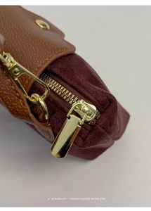 Close-up of brown lychee leather and burgundy suede patchwork with gold hardware