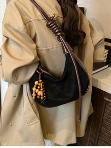 Chic black suede crescent bag with brown knotted strap and decorative beads on model