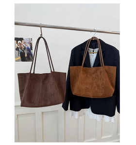 Detail of minimalist suede tote bags in brown and caramel hanging on a metal rack
