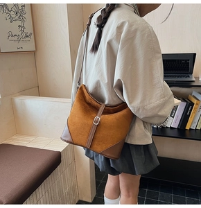 Détail du sac seau vintage en daim marron avec coutures et boucle argentée élégante