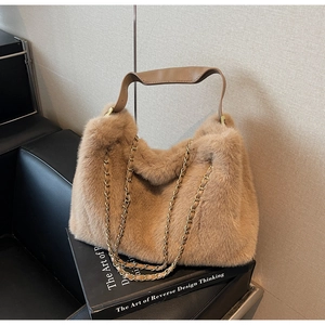 Detailed close-up of fluffy faux fur tote bag with gold chain strap on a black book