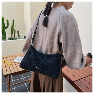 Detail of a black hobo bag with gold hardware worn as a stylish underarm bag
