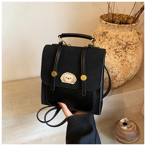 Detail eines schwarzen Mini-Rucksacks mit goldenen Knöpfen und süßem Hunde-Aufnäher