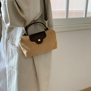 Detailed view of camel suede cross body bag with dark brown leather flap and golden hardware