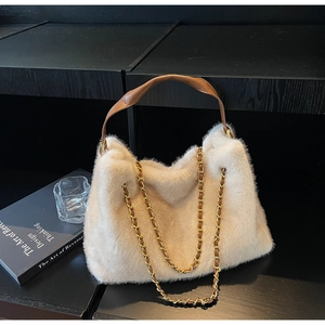 Detail of cream faux fur tote bag with brown leather handle and gold chain strap