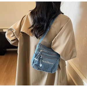 Detail of blue denim crossbody bag with multiple zippers and embroidered HanChaoJi logo