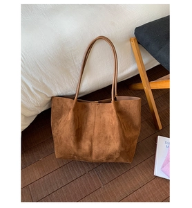 Detail of large brown suede tote bag featuring slim shoulder straps and vertical stitching