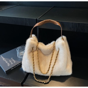Detail of white faux fur tote with brown leather handles and gold metal chain strap