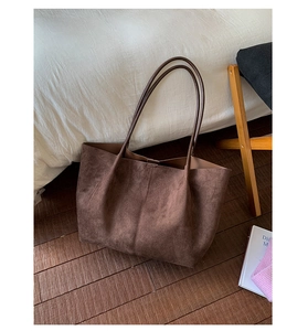 Detailed view of dark brown suede tote bag with textured surface and vertical stitching