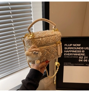 Detail of champagne gold tweed handbag with sequins, metal chain strap and fur charm