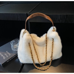 Detail of white faux fur tote bag with brown leather handles and gold metal chain strap