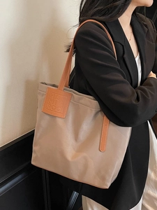 Chic beige tote bag with brown leather straps shown on shoulder for large capacity commute
