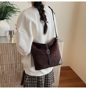 Détail du sac hobo en daim marron foncé avec coins en cuir et boucle argentée