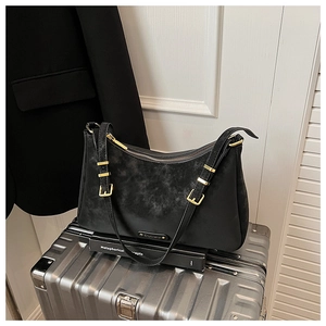 Close-up of black suede crossbody bag featuring gold zipper and metal buckle details