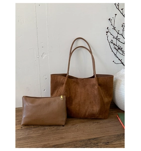 Close-up of brown suede tote bag and matching faux leather zipper pouch on a wooden table