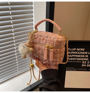 Detailed close-up of pink tweed crossbody bag with gold chain strap and fluffy doll charm