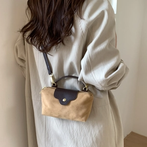 Detail of suede handbag showing contrast brown leather straps and gold metal hardware