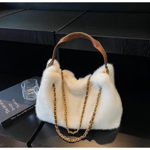 Detail of white faux fur tote bag featuring brown leather handle and gold chain strap
