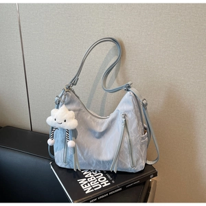 Detail of light blue nylon hobo bag with silver zippers and a cloud plush charm on books