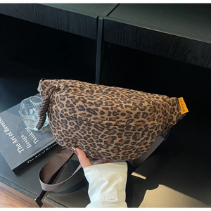 Detail of leopard print waist bag with orange logo tag and thick rope zipper pull on desk