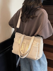 Beige corduroy tote bag with dual front zippers and wide strap shown on a model