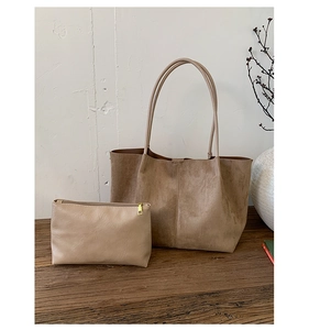 Detailed set of suede tote bag and matching zipper pouch on a rustic wooden bench