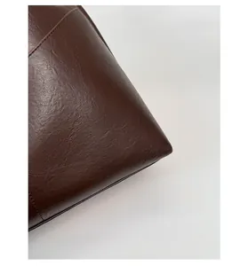 Detail shot of brown vintage leather bag showing fine stitching and textured material