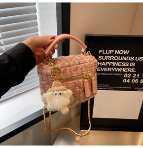 Detail of pink tweed mini bag with golden chain strap and cute plush charm accessory