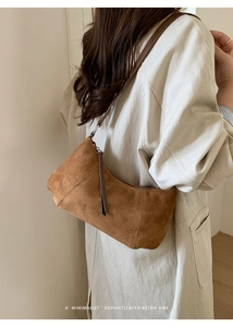 Détail du sac hobo en daim marron montrant la texture douce et la fermeture à gland