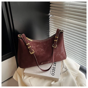 Detailed close-up of burgundy suede hobo bag with golden hardware and brand logo